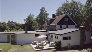 A two-story house with a patio area featuring outdoor furniture.