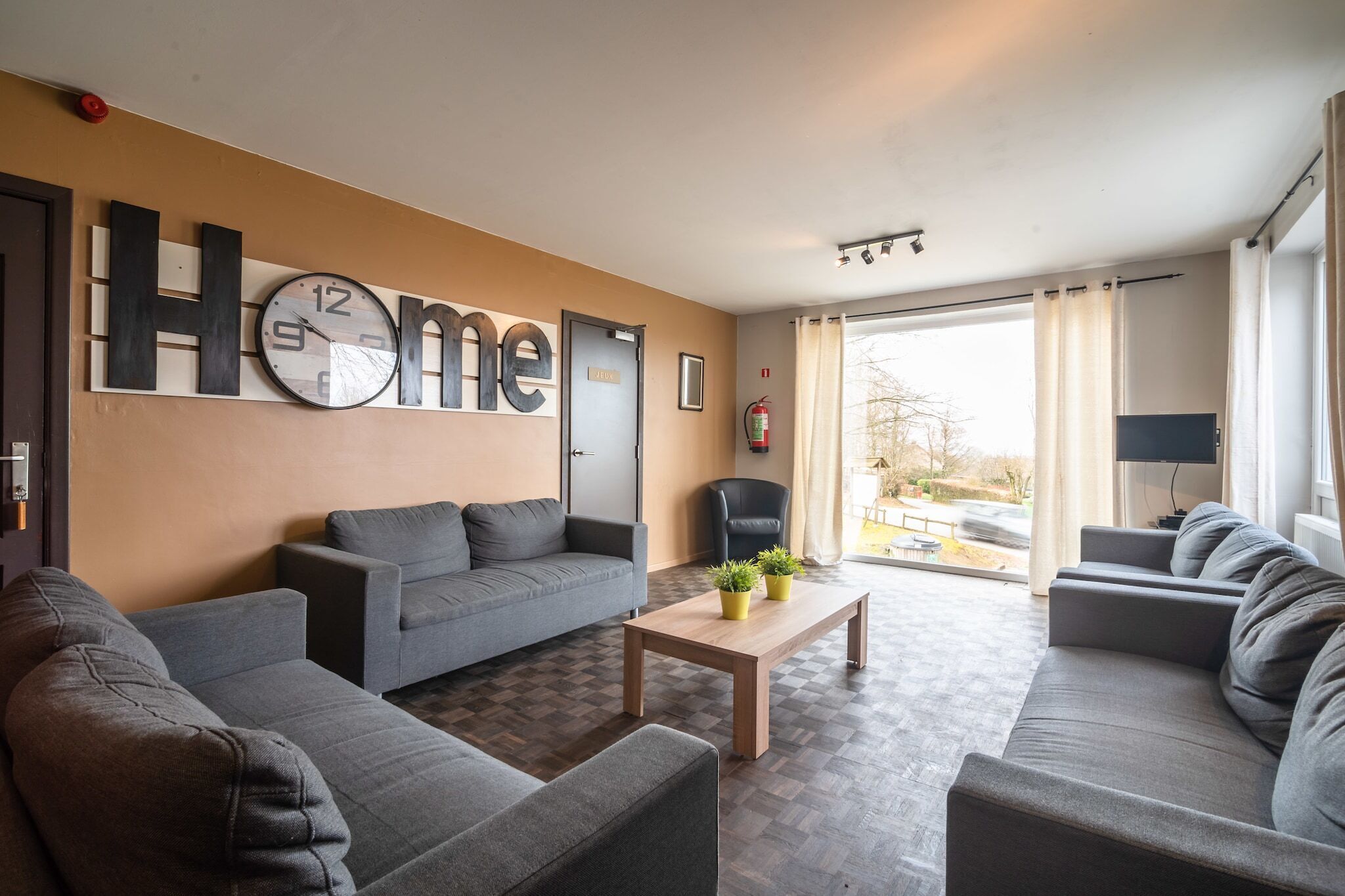 A modern living room with a large clock, a sofa set, a coffee table, and a television.