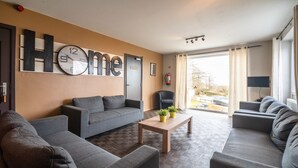 A modern living room with a large clock, a sofa set, a coffee table, and a television.