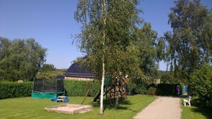 Un jardin bien entretenu, doté d’un espace de jeux comprenant une balançoire et un bac à sable.