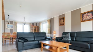 A living room with two black sofas, a wooden coffee table, and a dining area with a wooden table and chairs. - Spacious Holiday Home in Chodes with Sauna (Malmédy-Boussire)