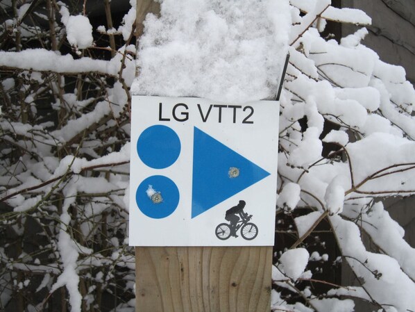 Ein Schild mit Symbolen und Text, umgeben von schneebedeckten Ästen.