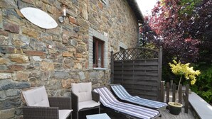 A stone building with a patio area featuring wicker furniture and a small table.