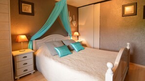 A neatly made bed with a canopy, two bedside lamps, and a nightstand with drawers.