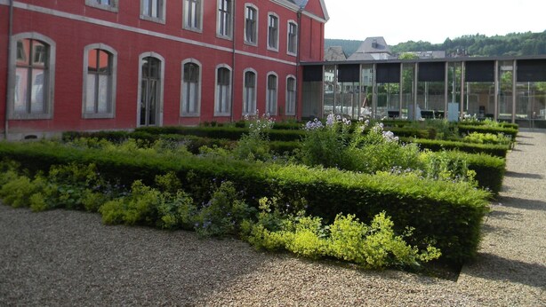 A red building with arched windows and a modern glass structure in the background.