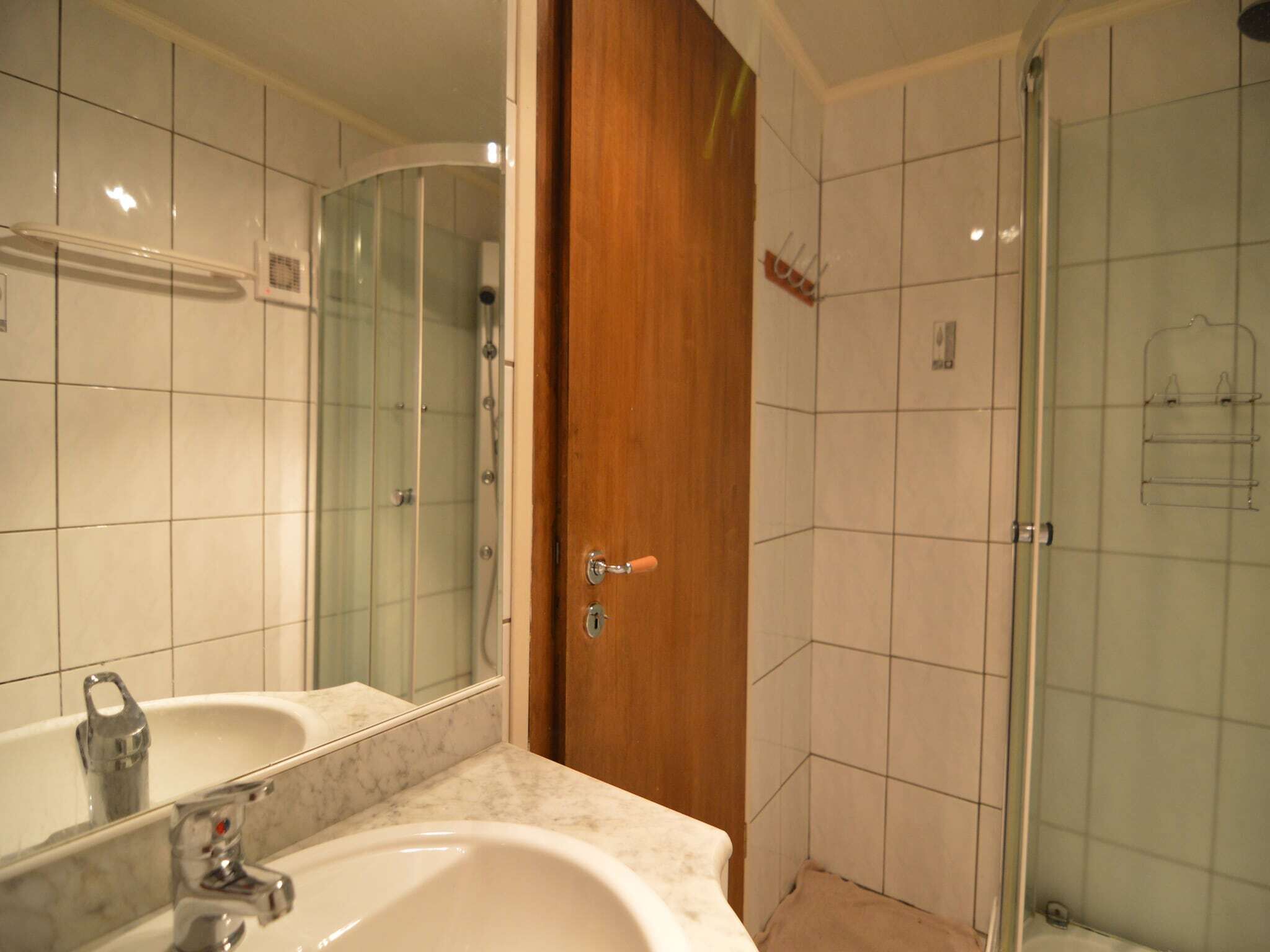 Une salle de bain avec un grand miroir, un lavabo et une douche en verre.