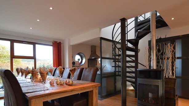 A dining area with a wooden table and chairs, a spiral staircase, and a fireplace. - Holiday Home in Stoumont with Private Pool (Stoumont)