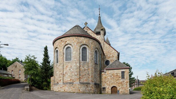 A stone church with a bell tower and a rounded main building.