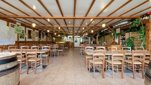 A restaurant with wooden tables and chairs, a tiled floor, and a ceiling with wooden beams.