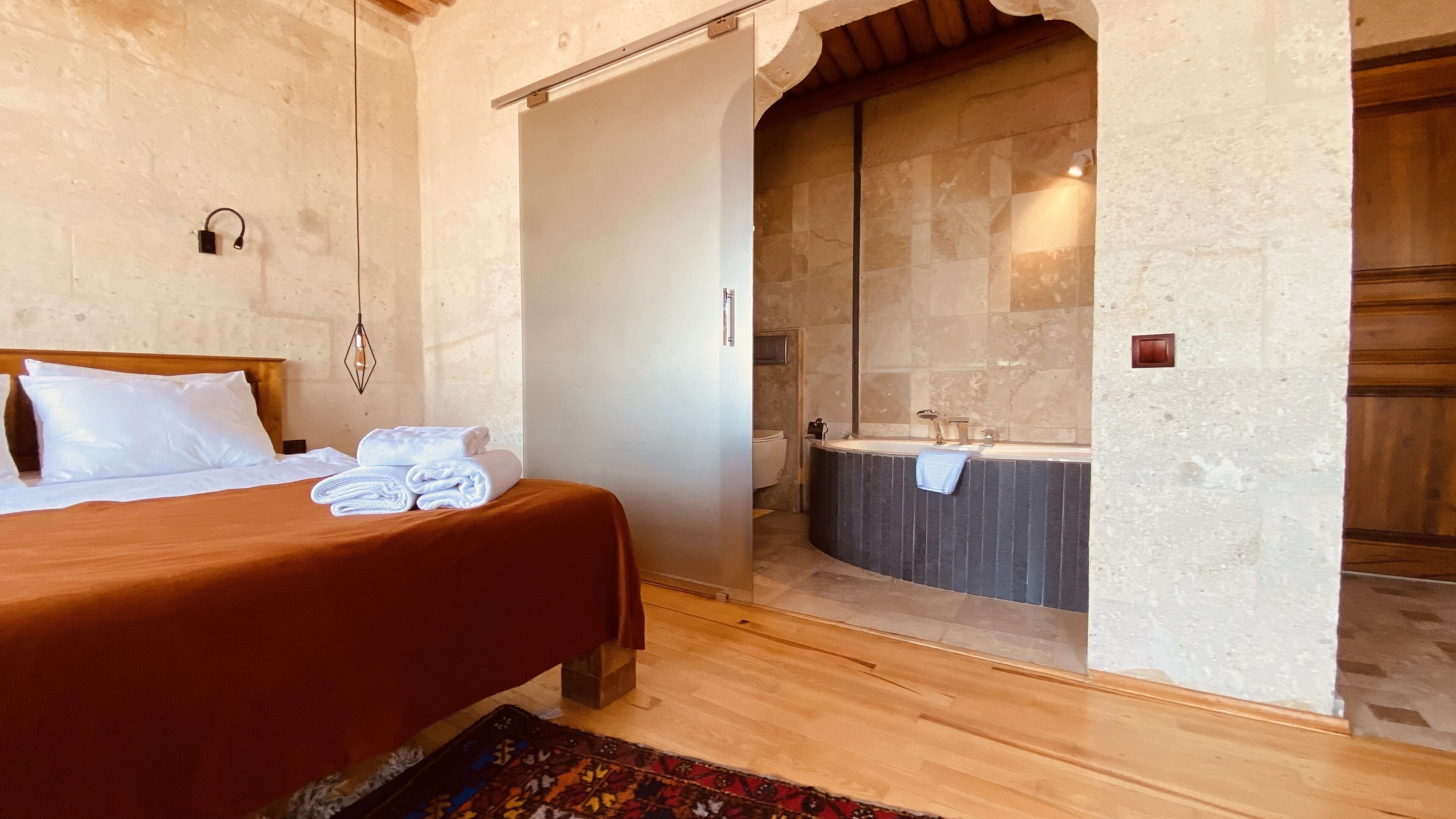 Una habitación con cama, baño con bañera y suelo de madera.