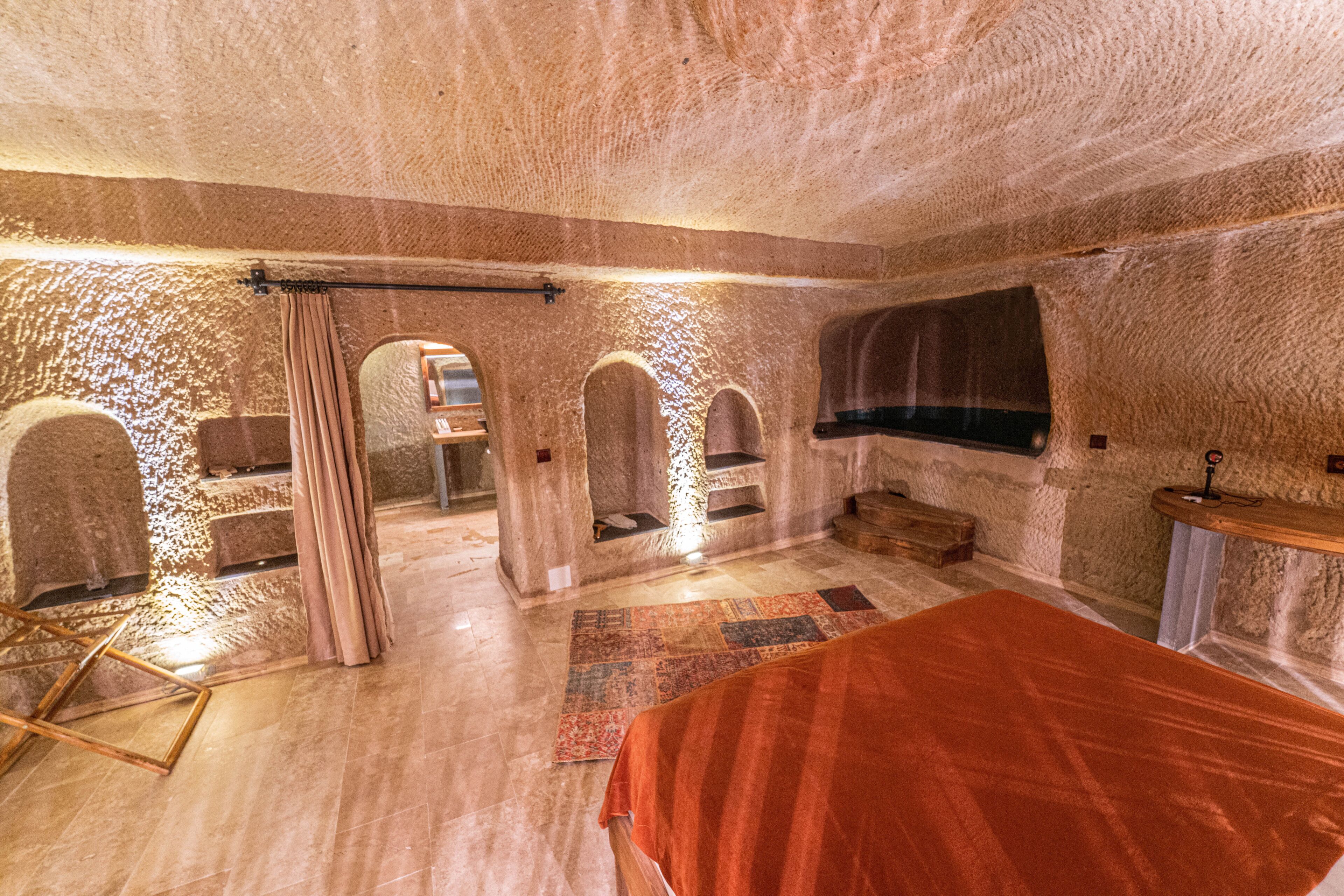 A room with stone walls, a bed, a wooden chair, and a small table.