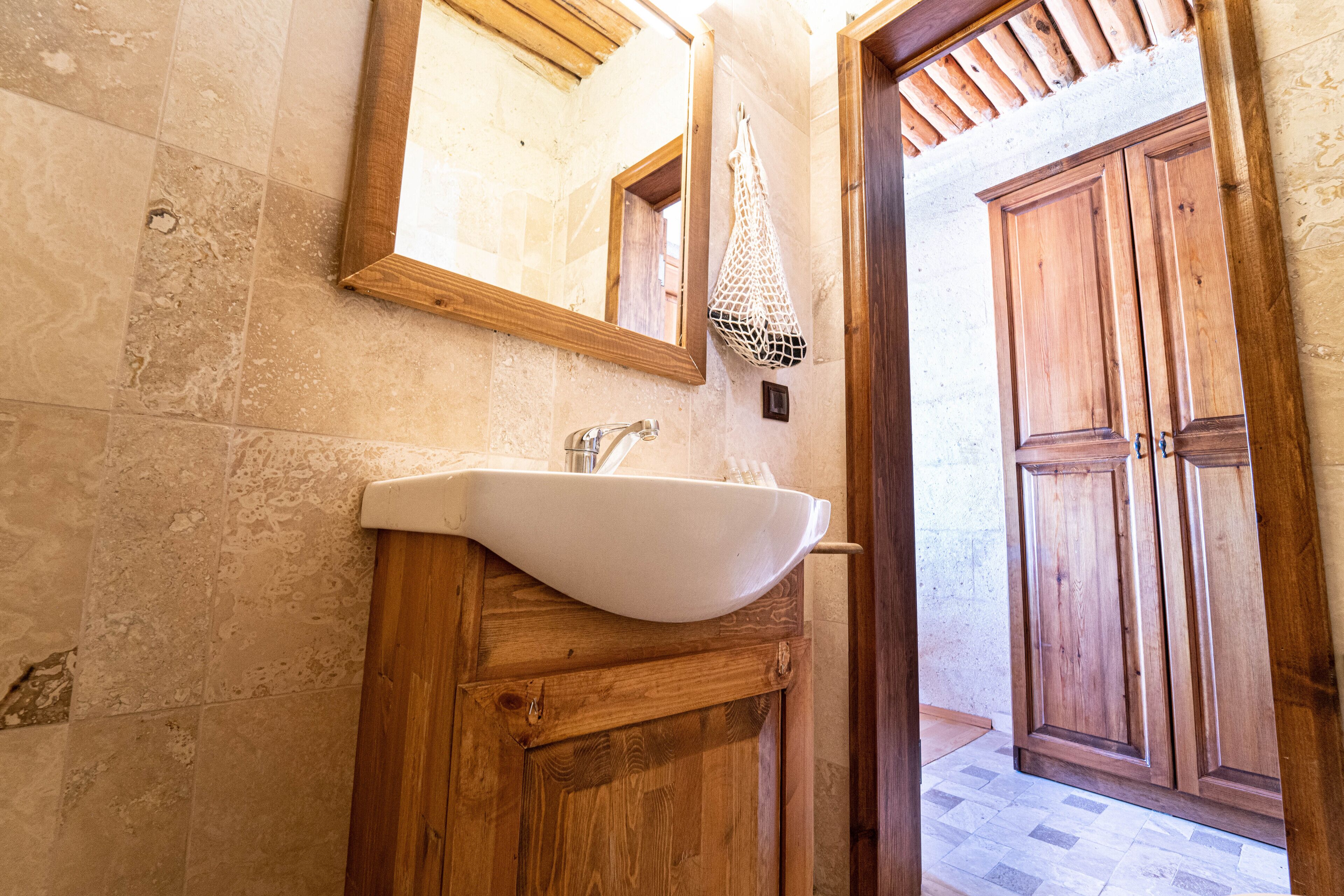 A bathroom with a wooden vanity, a white sink, and a wooden door.