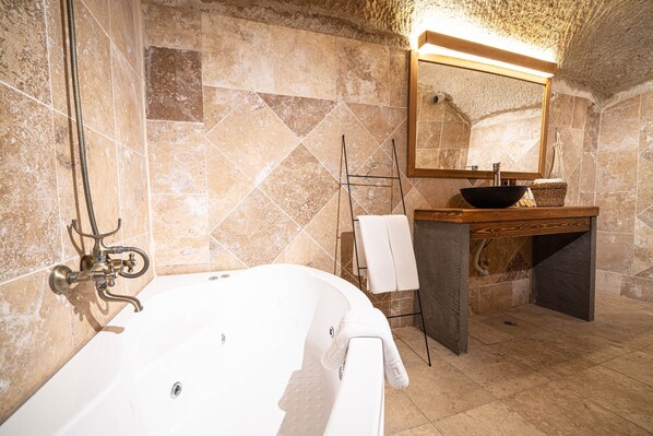 A bathroom with a bathtub, a wooden vanity, a mirror, and a towel rack. - Alice in Cappadocia (Nevsehir)