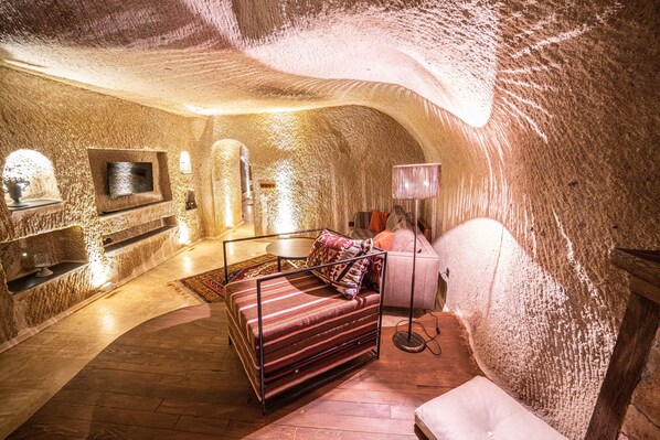 Un dormitorio acogedor, tipo cueva, con una cama, un televisor y una lámpara.