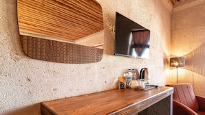 A wooden counter with a patterned wall behind it, a flat-screen TV mounted on the wall, and a red chair to the right. - Alice in Cappadocia (Nevsehir)
