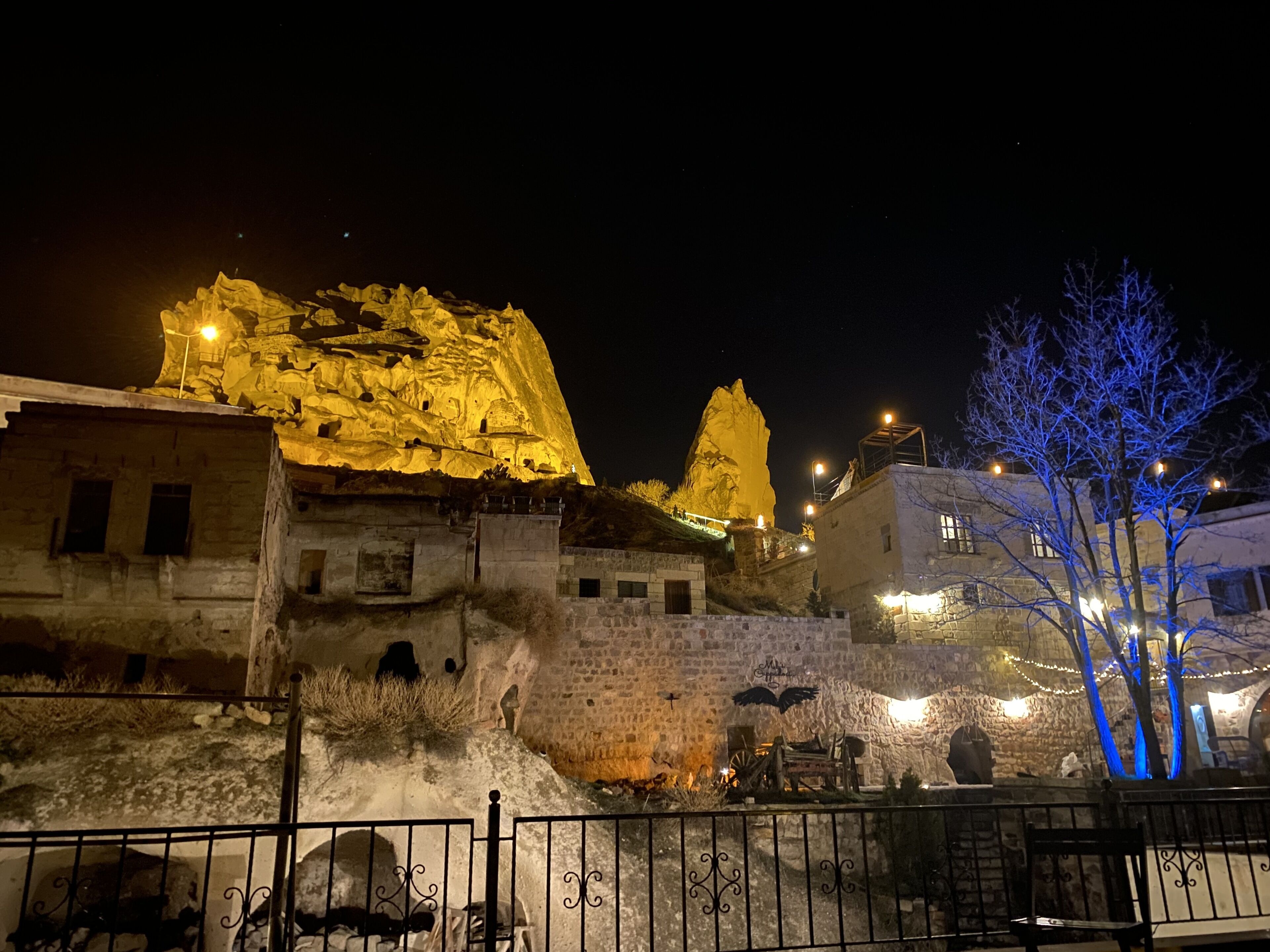 A historic building with illuminated rock formations and a stone wall.
