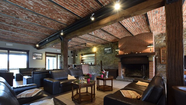 Una sala de estar acogedora con sofás de cuero, chimenea y techos de ladrillo visto.