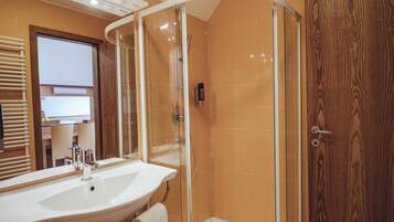 Un baño moderno con ducha de vidrio, un lavamanos grande y una puerta de madera.