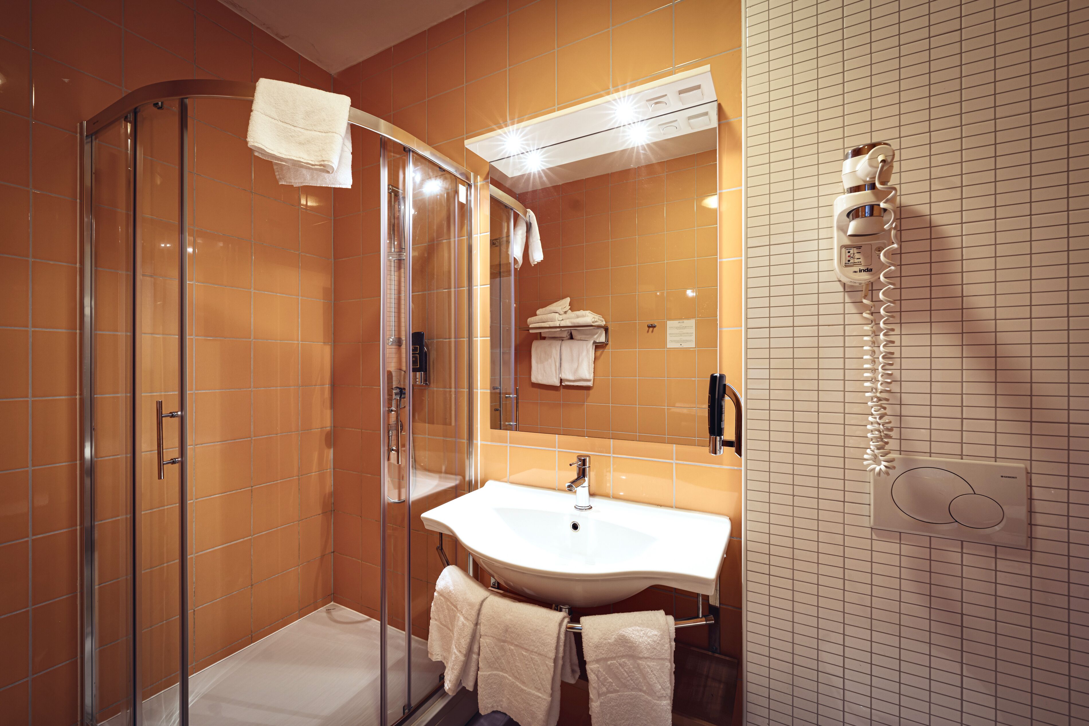 A bathroom with a glass shower enclosure, a sink, and a towel rack.