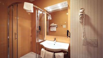 A bathroom with a glass shower enclosure, a sink, and a towel rack.