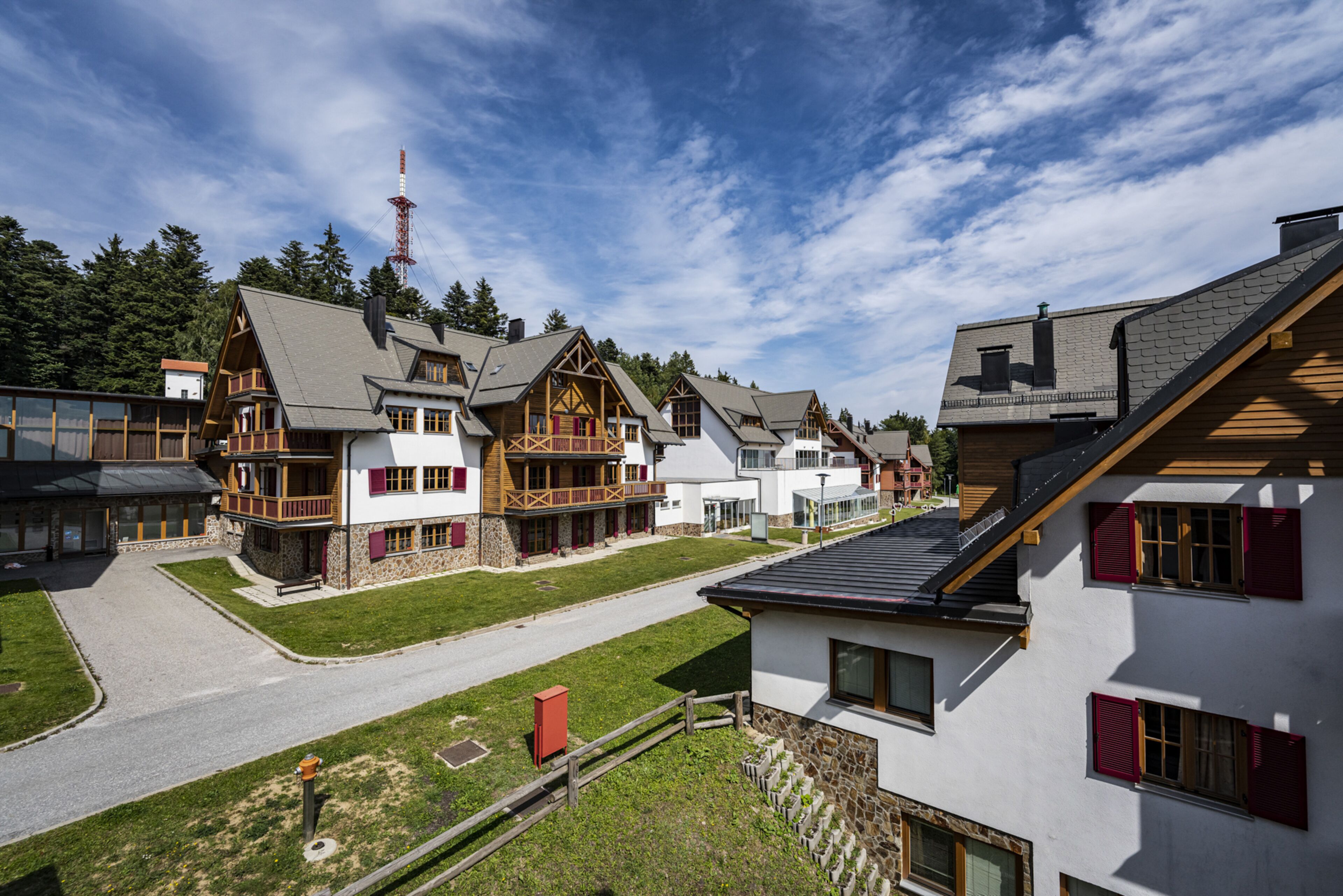 A row of chalet-style buildings with balconies, wooden facades, and a clear sky.