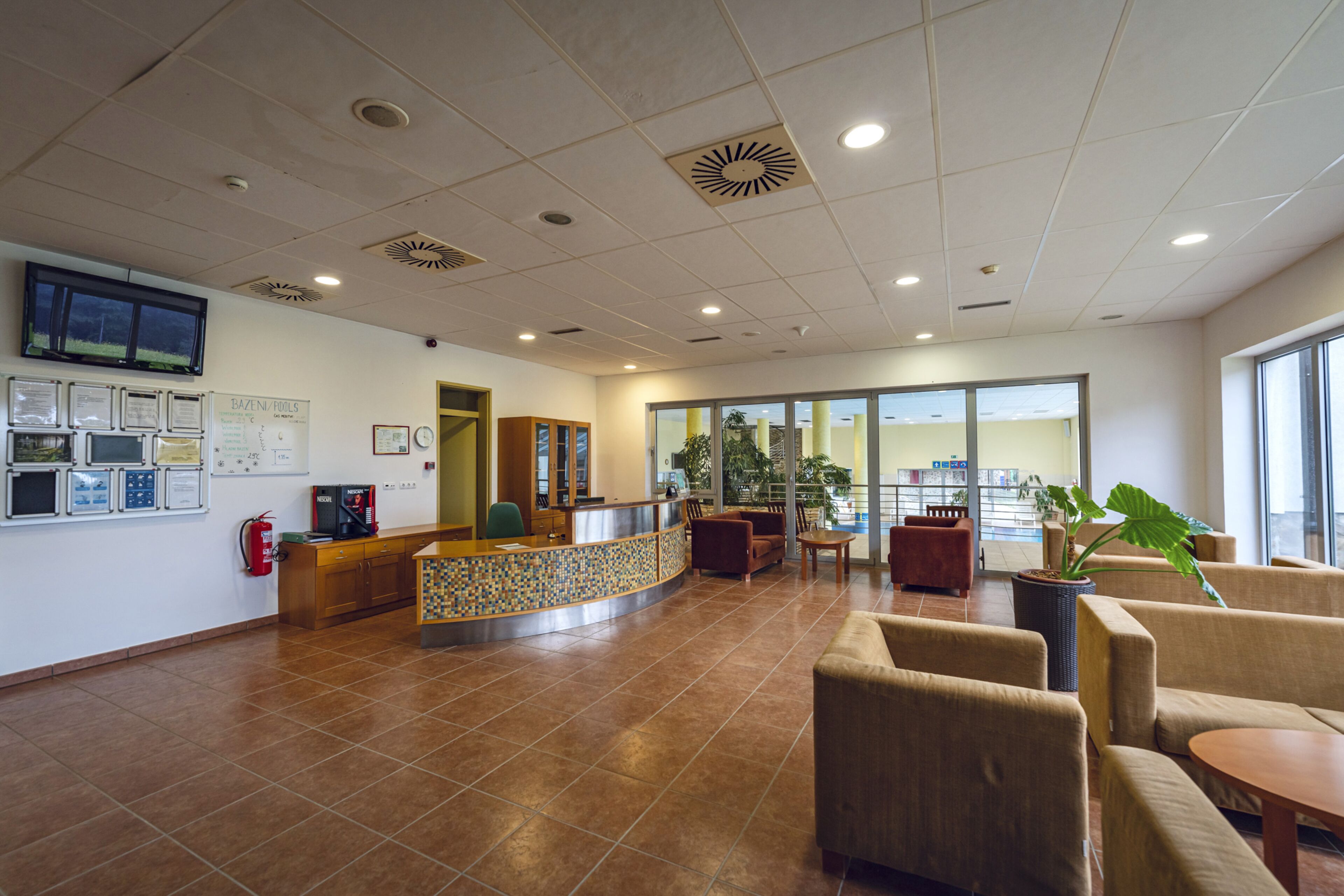 A reception area with a tiled floor, a reception desk, seating area, and a large window.