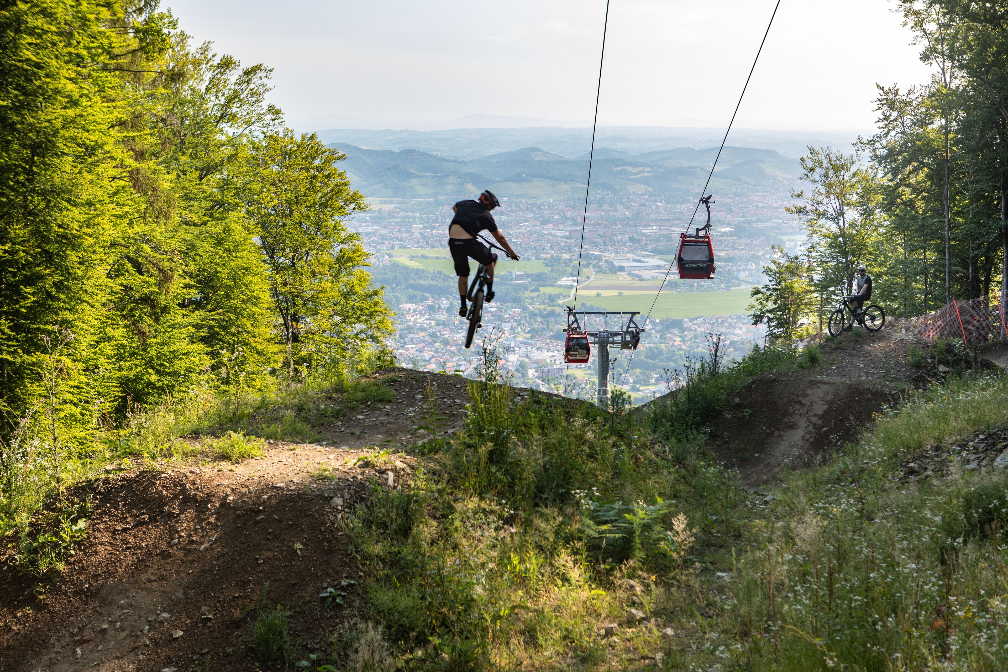Un sentier de VTT avec une télécabine en arrière-plan.