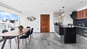 A modern kitchen with a central island, black cabinets, and a wooden door.