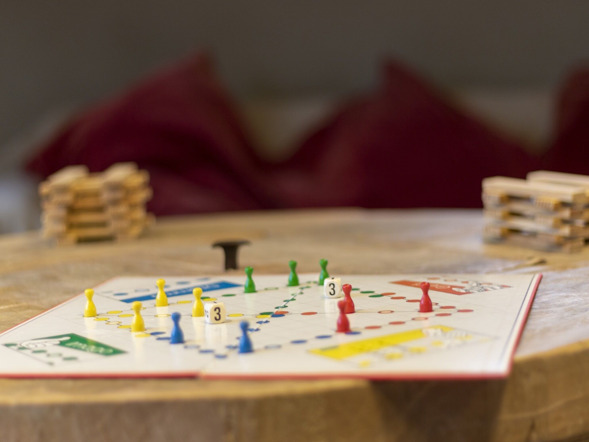 Jogo de tabuleiro em andamento sobre uma mesa de madeira, com fundo desfocado.