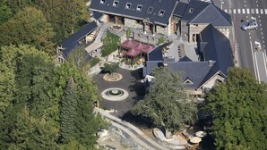 Une vue aérienne d’un grand immeuble à plusieurs étages, doté d’une cour intérieure et entouré d’une forêt dense.