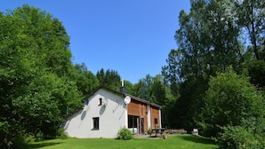 Ein eingeschossiges Haus mit geneigtem Dach, Satellitenschüsseln und einer kleinen Veranda.