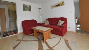 A living room with a red sofa, a wooden coffee table, and a patterned rug.