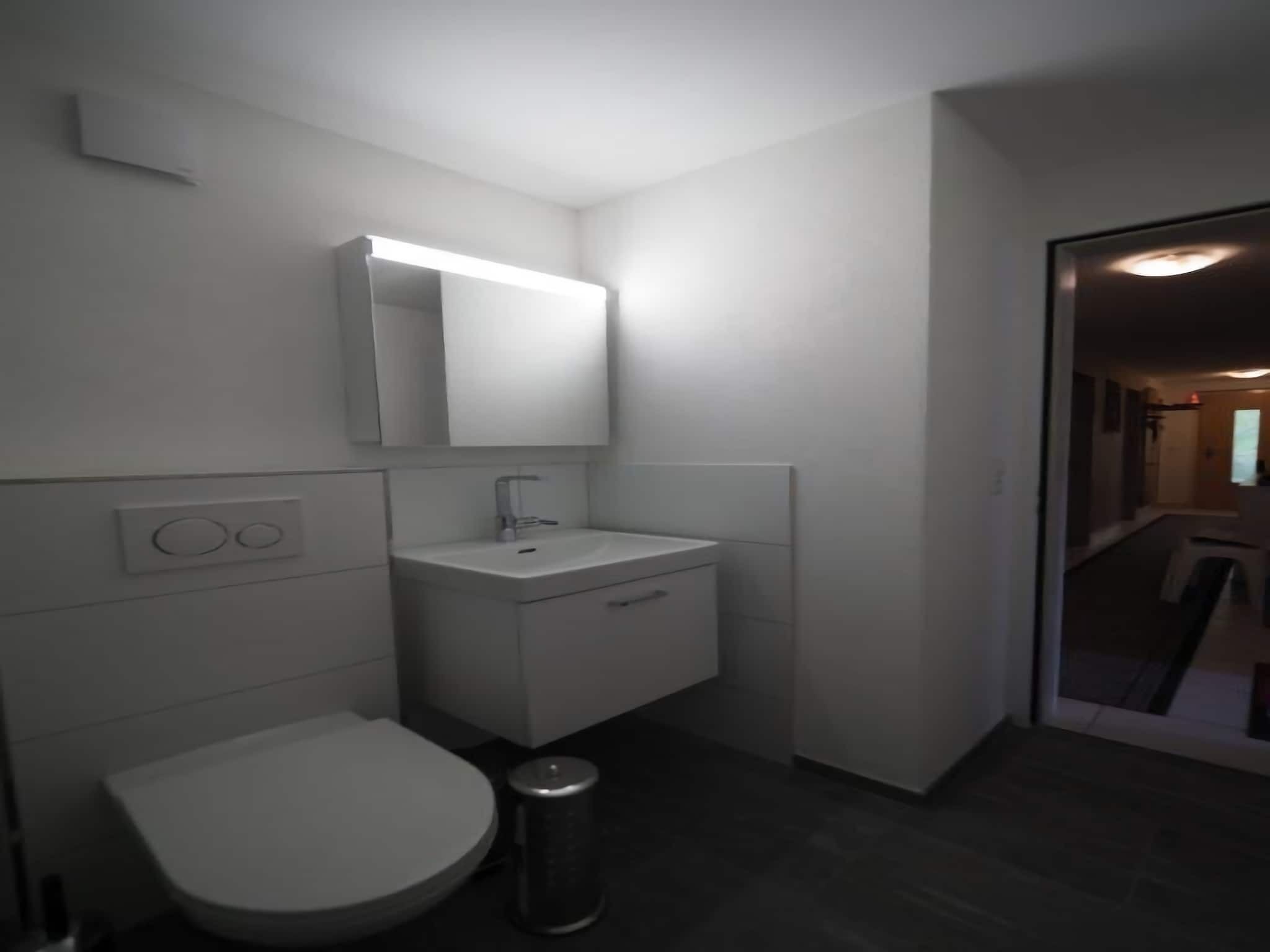 Un baño pequeño y moderno con inodoro, lavamanos y espejo.
