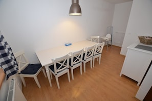 Comedor con una mesa blanca, seis sillas, una lámpara colgante y un radiador.