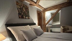 Et soveværelse med seng, et natbord, en stol, et billede og et vindue.