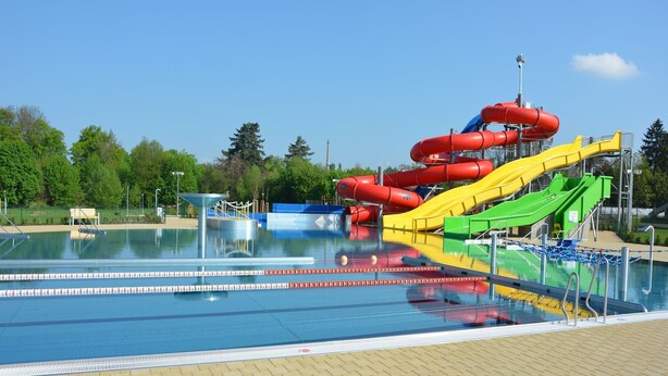 Una piscina con varias toboganes y una torre de salvavidas.