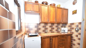 Cocina compacta con muebles de madera, refrigerador blanco y salpicadero de azulejos.
