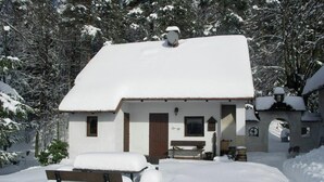 Un pequeño edificio cubierto de nieve con un banco de madera al frente.