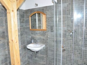 A bathroom with a wooden beam, a sink, a mirror, and a shower. - Spacious Group Retreat (Dlouhý)