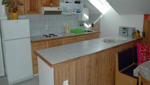 A compact kitchen with wooden cabinets, a built-in oven, a sink, and a small island with a cutting board. - Spacious cottage in the Giant Mountains, 1 km from the skislopes (Jestřabí V Krkonoších)