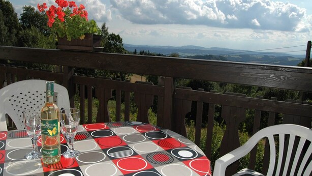 A round table with a checkered tablecloth, two chairs, a bottle of vodka, and glasses on a balcony with a view of the landscape. - Spacious cottage in the Giant Mountains, 1 km from the skislopes (Jestřabí V Krkonoších)