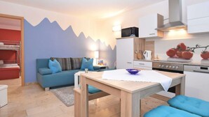 A compact living space with a kitchenette, a dining area, and a sofa with blue cushions. - Gartenhaus in Lichtenhain (Lichtenhain)