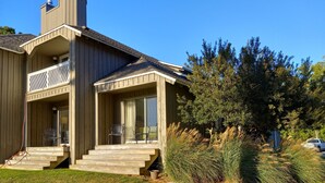 A two-story wooden house with a covered porch, a chimney, and a car parked in the driveway. - Walk to beach, cozy, lovely room in "Kingsmill on the James" (Williamsburg)