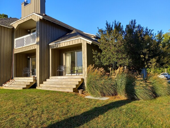 A two-story wooden house with a covered porch, a chimney, and a car parked in the driveway.