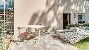 An outdoor patio with a table and chairs, a metal ladder, and a stone pathway leading to a house. - Tranquil Stay in Dörnthal (Pfaffroda Ot Dörnthal)