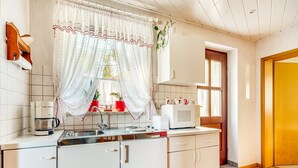 A kitchen with white cabinets, a coffee maker, a microwave, and a sink. - Tranquil Stay in Dörnthal (Pfaffroda Ot Dörnthal)