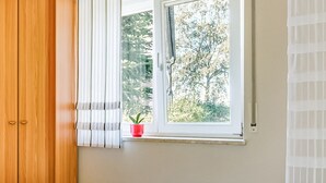 A room with a wooden wardrobe, a window with a white blind, and a potted plant on the windowsill. - Tranquil Stay in Dörnthal (Pfaffroda Ot Dörnthal)