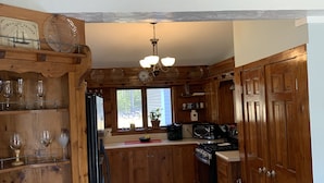 Una cocina con armarios de madera, un refrigerador, una estufa y una ventana con vista a árboles.