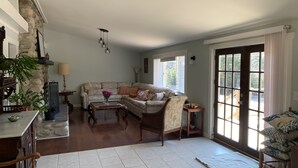 Un salón espacioso con pared de piedra, un sofá, una mesa de centro y vistas a través de un ventanal grande.
