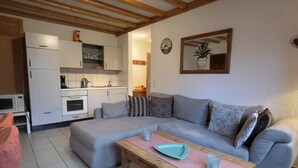 A living room with a grey sofa, a wooden coffee table, and a kitchen in the background. - Flat in Meisberg with in-house catering (Meisburg)